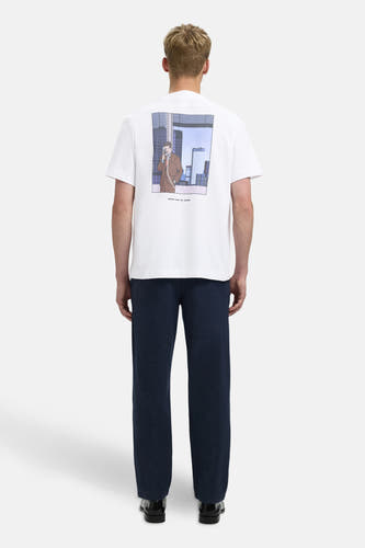 T-shirt blanc à manches courtes de SELECTED, avec illustration sur le dos, associé à un pantalon bleu marine et des chaussures noires.