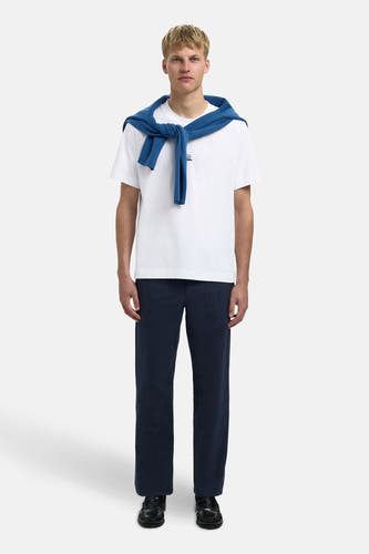 T-shirt blanc à manches courtes de SELECTED, avec un pull bleu nonchalant sur les épaules et un pantalon bleu marine.