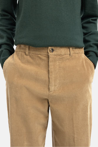 Pantalon brun de SELECTED, texture corduroy, avec des poches et une chemise verte tricotée.