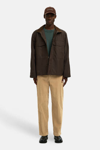 Pantalon brun de SELECTED, avec un fini velours côtelé, porté avec une veste br et une truiue verte.