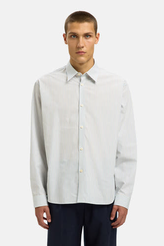 Chemise blanche à manches longues de SELECTED, rayée de lignes bleu clair, associée à un pantalon bleu marine et des chaussures noires.