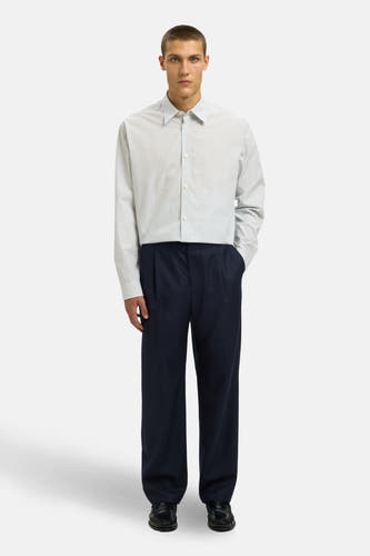 Chemise blanche à manches longues de SELECTED, avec des rayures bleues, portée avec un pantalon bleu marine.