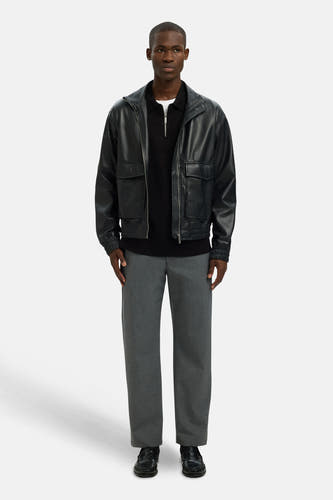 Pull-over noir avec col rond de SELECTED, porté sous une veste en cuir et associé à des pantalons gris et des loafers noirs.