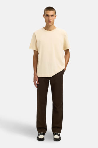 T-shirt beige à manches courtes de SELECTED, associé à un pantalon marron et des loafers en cuir.