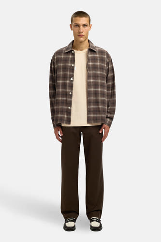 T-shirt beige à manches courtes de SELECTED, porté sous un chemisier à carreaux avec des pantalons marron et des loafers.