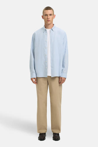Blauw overhemd met lange mouwen van SELECTED, gedragen over een wit T-shirt, met beige broek en leren loafers.