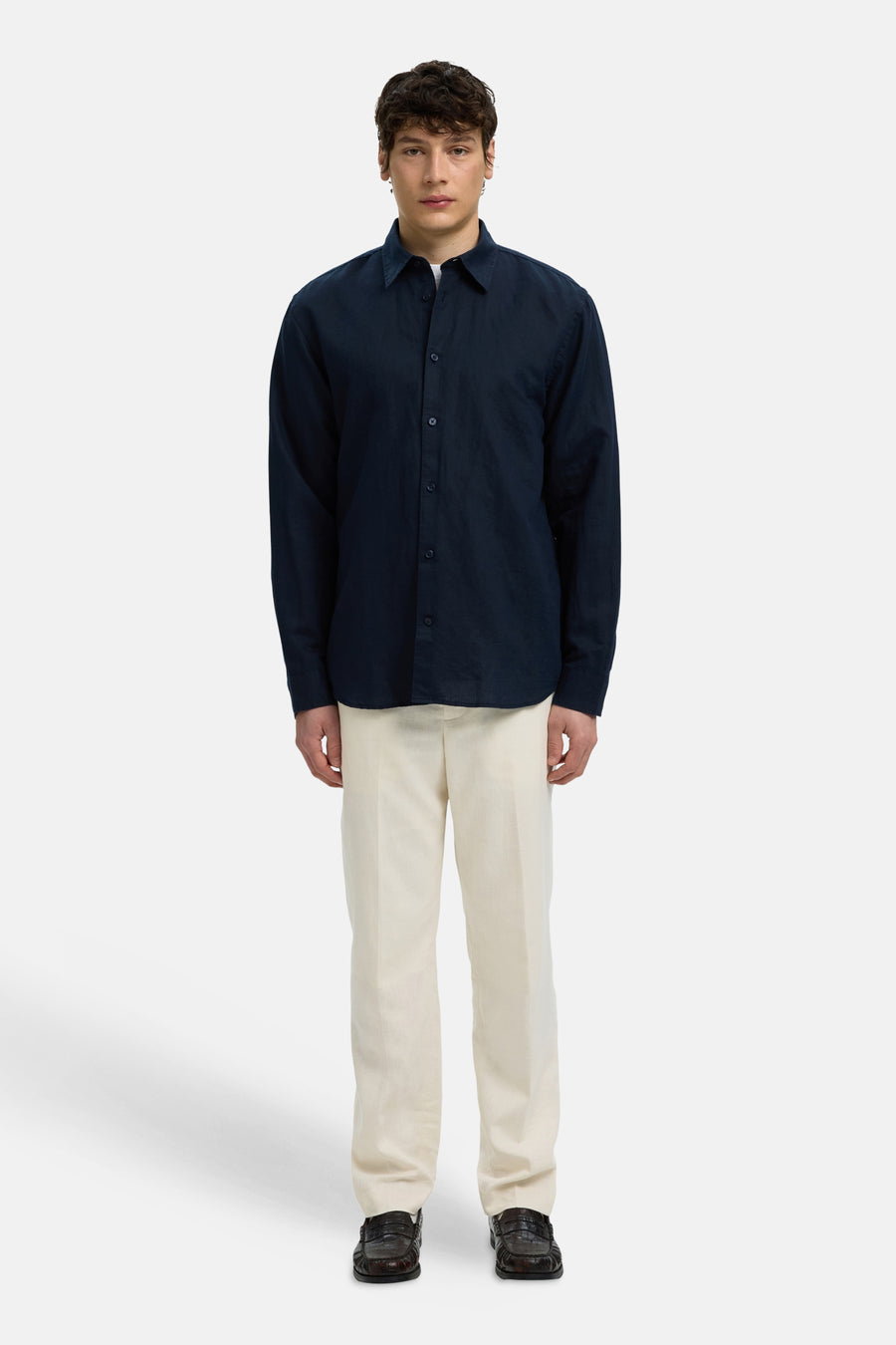 Chemise bleue à manches longues de SELECTED avec une texture légère, portée par un mannequin avec un pantalon crème et des mocassins foncés.