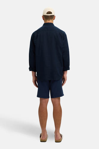 Chemise bleue à manches longues de SELECTED, coupe décontractée, portée avec un short bleu et des sandales.