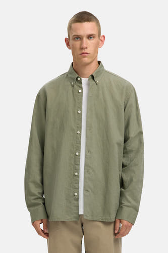Chemise verte à manches longues de SELECTED, avec un tissu légèrement texturé et une ouverture boutonnée au-dessus d'un t-shirt blanc.