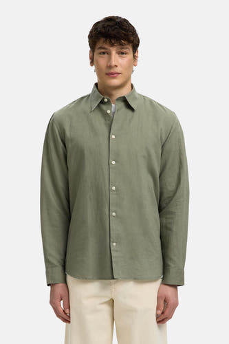 Chemise verte à manches longues de SELECTED avec boutons blancs et col ouvert, portée sur un pantalon clair.