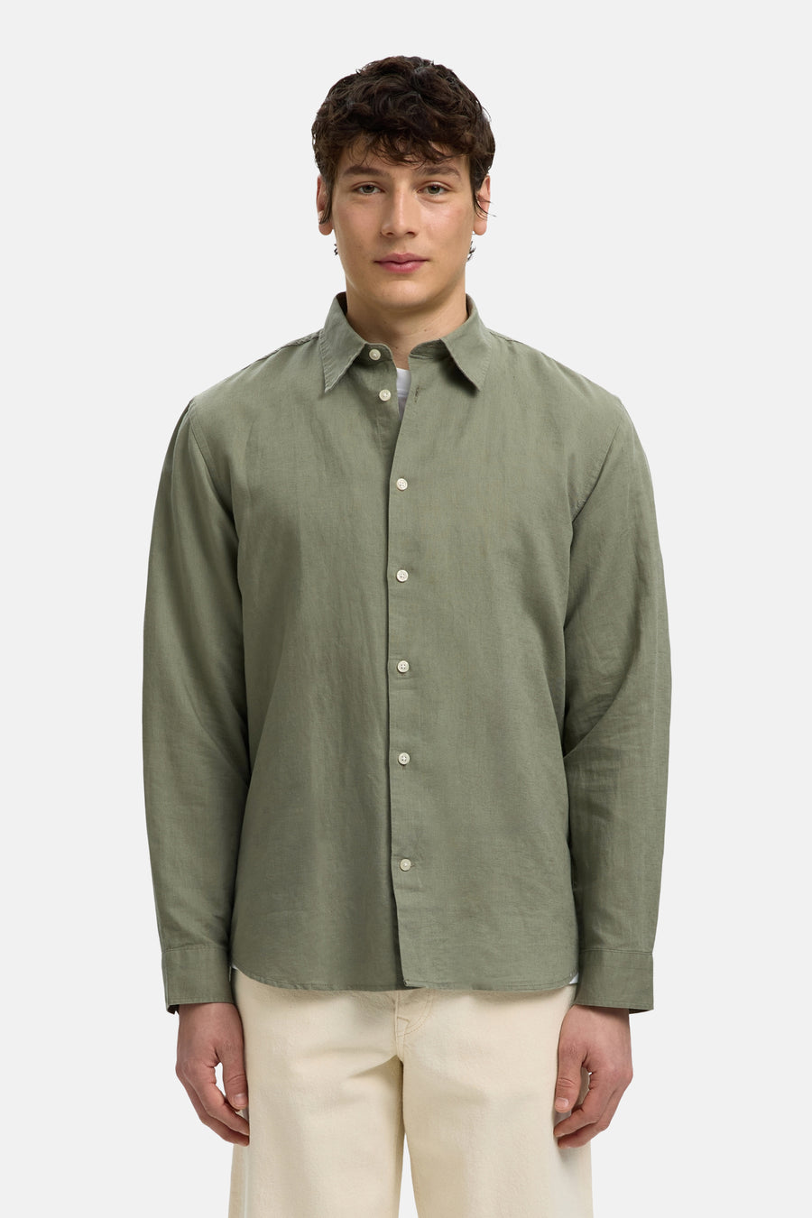 Chemise verte à manches longues de SELECTED avec boutons blancs et col ouvert, portée sur un pantalon clair.