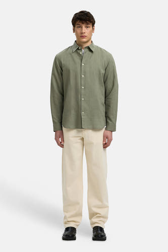 Chemise verte à manches longues de SELECTED, avec une texture légère, combinée avec un pantalon beige et des mocassins noirs.