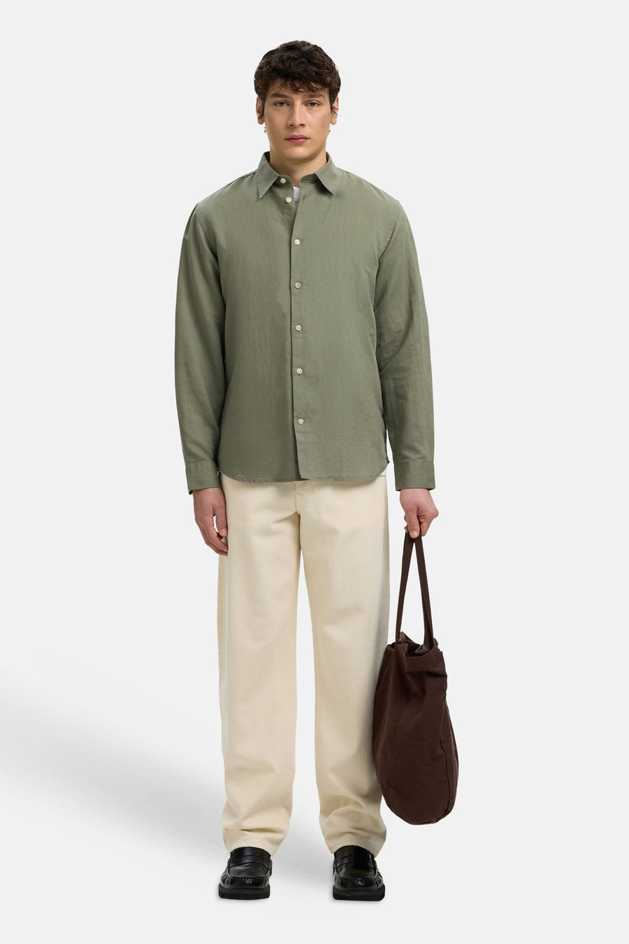 Chemise verte à manches longues de SELECTED, combinée avec un pantalon crème, des mocassins noirs et un sac marron.
