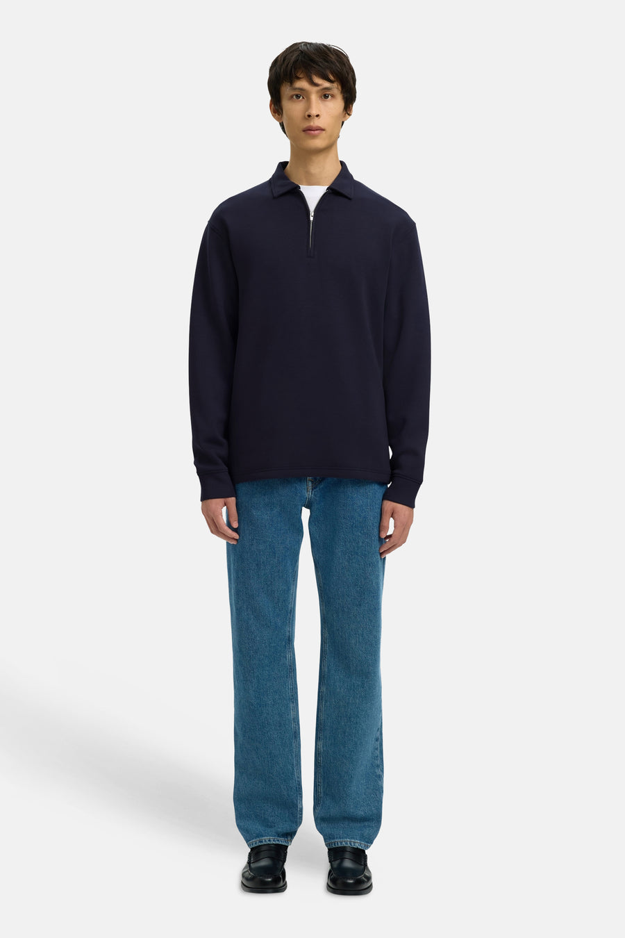 Blauwe sweater van SELECTED, gedragen met een wit T-shirt, blauwe jeans en zwarte schoenen.