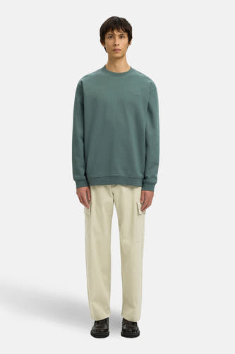 Groene sweater met ronde hals van SELECTED, gedragen met beige cargo broek en donkere loafers.
