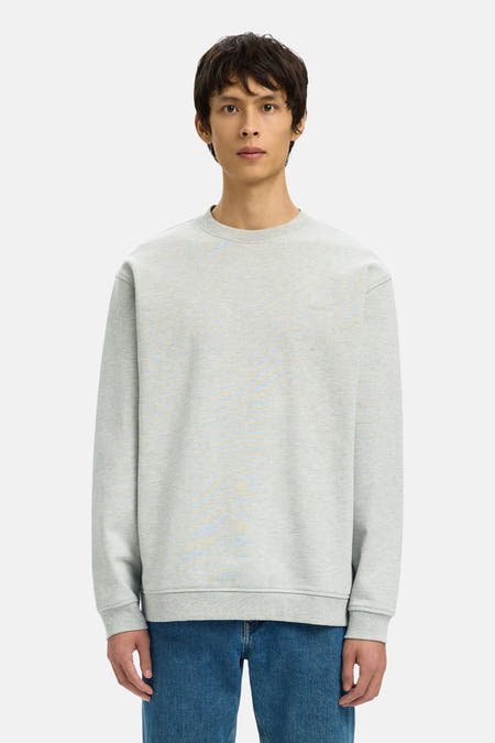 Pull gris à col rond de SELECTED, porté avec un jean bleu et des mocassins noirs.