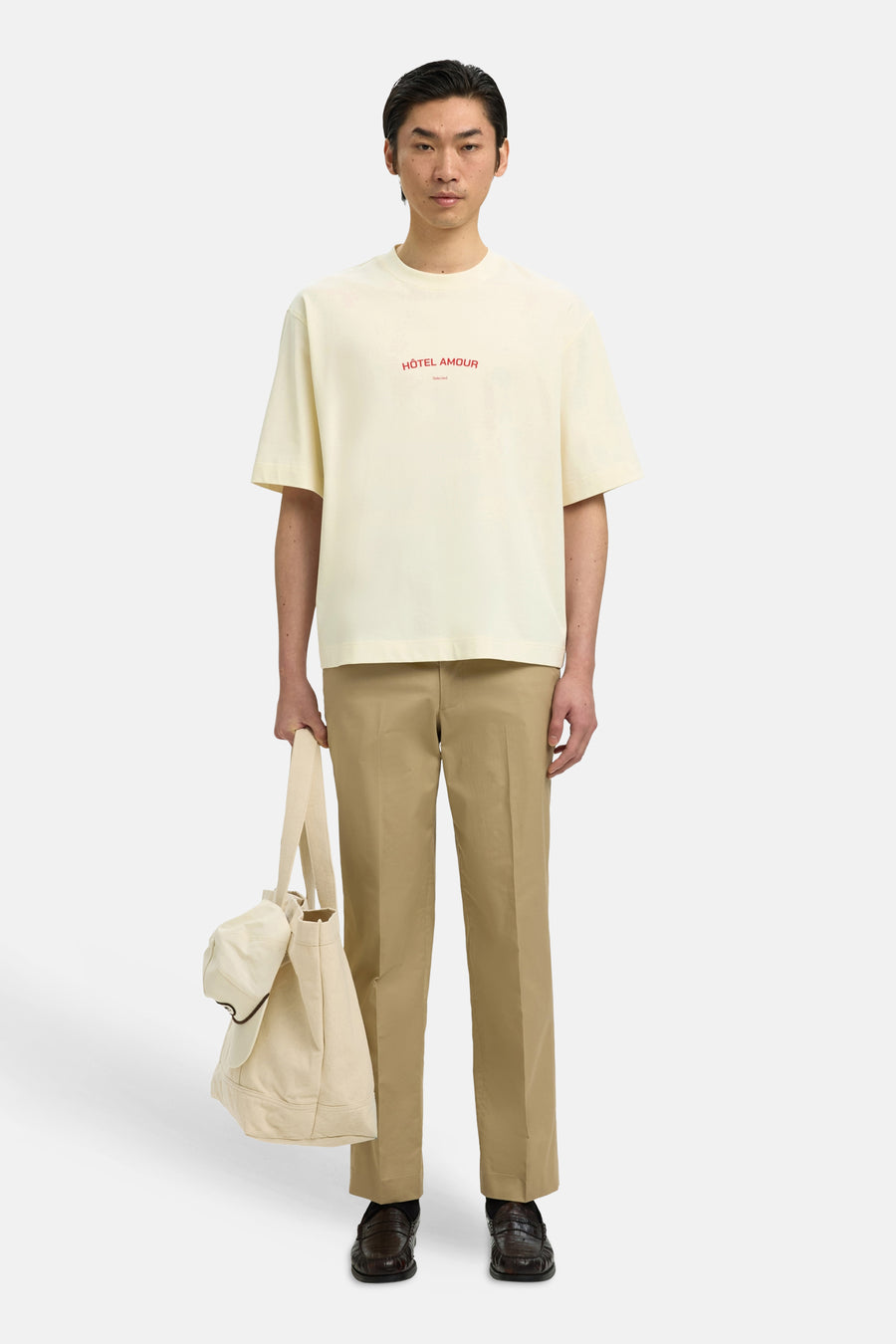 T-shirt écru de SELECTED, avec imprimé rouge, combiné avec un pantalon beige et un tote bag écru.