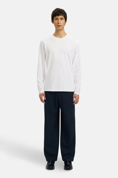 T-shirt blanc à manches longues de SELECTED, porté avec un pantalon bleu marine et des loafers noirs.