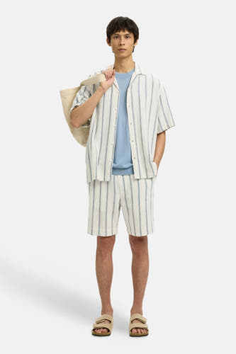 Chemise écru à manches courtes de SELECTED, rayée, portée sur un pull bleu clair, avec des sandales beiges et un sac.