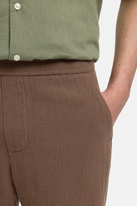 Bruine korte broek van SELECTED met geribde textuur, zijzak en elastische taille, gedragen met groen overhemd, close-up zijaanzicht