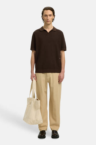 Polo marron de SELECTED, à manches courtes et avec un motif texturé subtil, combinée avec un pantalon beige et un sac en toile.
