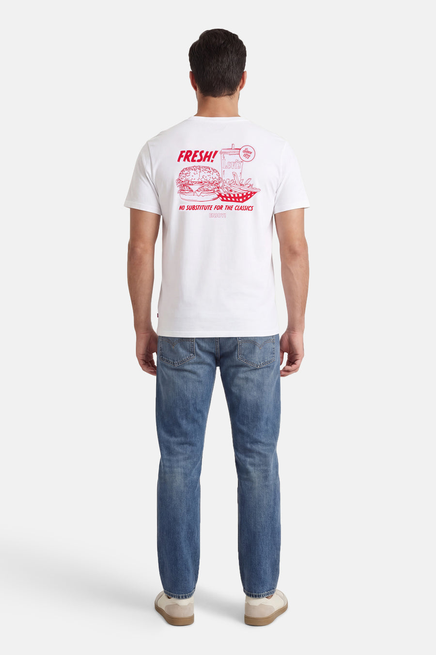 T-shirt blanc à manches courtes de Levi's, avec imprimé rouge au dos, porté avec un jean et des baskets.