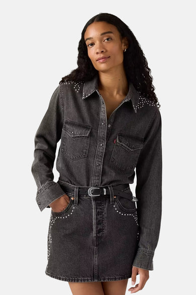 Blouson en denim noir à longues manches de Levi's®, orné de strass sur les épaules et les poches, associé à une jupe noire.
