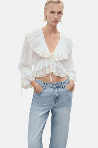 Jean large en denim bleu clair de MANGO, avec poches et porté avec une blouse blanche à détails.