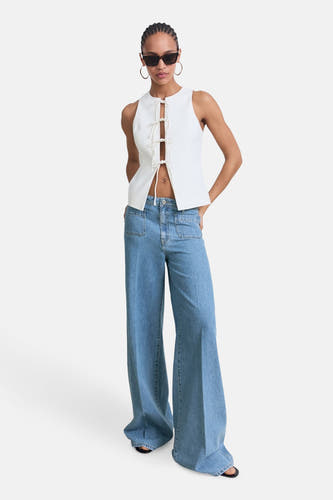 Jean décontracté de denim bleu MANGO, avec poches et porté avec un haut blanc et des lunettes de soleil.