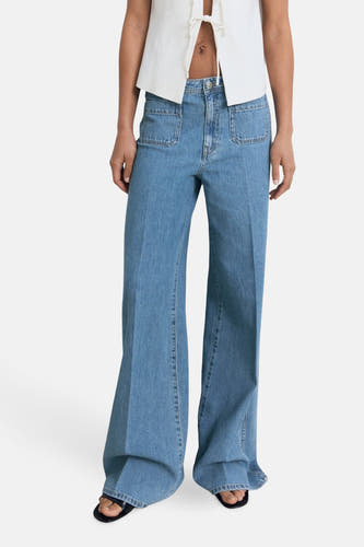 Jean large de MANGO en denim bleu, avec des poches et une chemise blanche.