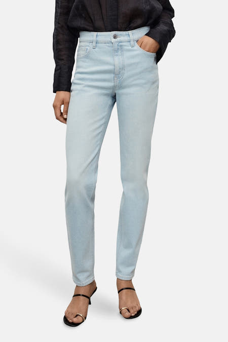 Lichtblauwe mom jeans denim van MANGO, gecombineerd met een zwarte blouse en zwarte sandalen met hak.