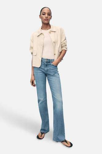 Jean délavé de denim bleu clair de MANGO, associé à une veste écru et des escarpins.