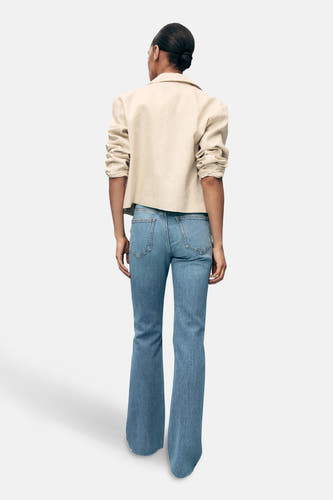 Jean délavé de denim bleu clair de MANGO, vu de derrière, associé à une veste blanche.
