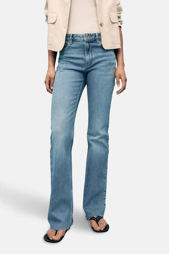 Jean flare bleu clair de MANGO, associé à un blazer beige et des sandales noires.