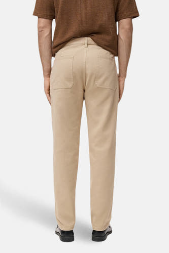 Pantalon beige de MANGO, vu de de l'arrière avec des poches arrière et des chaussures noires.