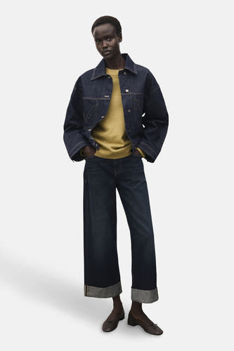 T-shirt vert avec col rond de MANGO, porté avec un blouson en denim et des jeans bleus marine à poches.