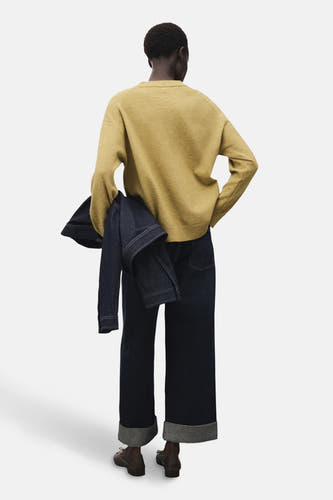 T-shirt vert avec col rond de MANGO, vu de derrière, avec un blouson en denim et des pantalons de jeans larges.