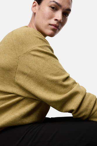 T-shirt vert avec col rond de MANGO, gros plan sur un modèle portant un pantalon noir.