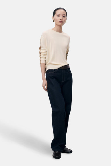 Gilet rond beige de MANGO, avec des rayures brunes sur les manches, associé à un jeans foncé avec ce ce.
