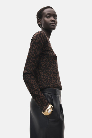 Pull marron avec col rond de MANGO, imprimé zèbre, associé à un pantalon en cuir noir et à un bracelet doré.