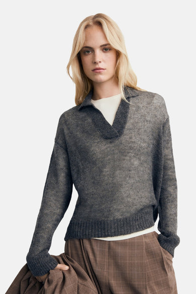 Sweat-shirt gris à col V de MANGO, en fine texture, porté sur un chemisier blanc et un pantalon kaki.