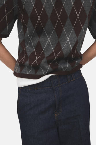 Sweat-shirt multicolore à col rond de MANGO, avec un motif carreaux d'argyle en brun, gris et blanc, porté avec un t-shirt blanc et un jean foncé.
