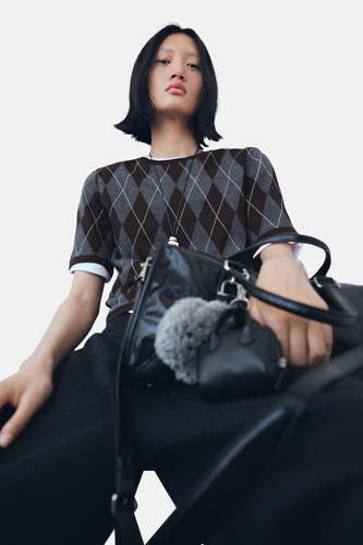 Sweat-shirt multicolore à col rond de MANGO, avec un motif à carreaux et une en blanche en dessous, associé à des pantalons noirs et un sac.