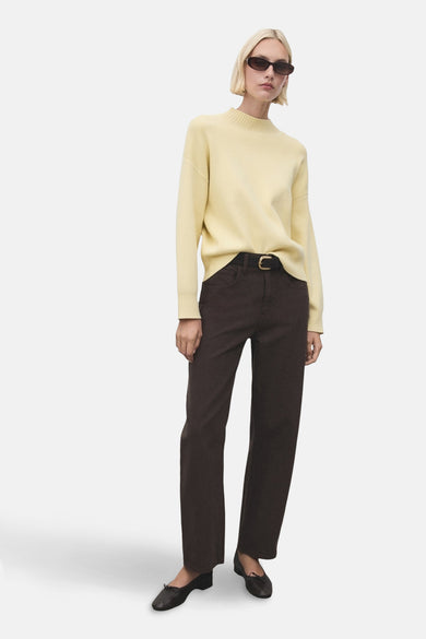 Gele trui met ronde hals van MANGO, gedragen met een bruine broek en zwarte ballerina's.
