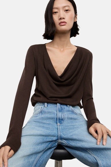 Sweat-shirt marron avec col rond de MANGO, porté par un mannequin en jeans bleus et les mains derrière le dos.