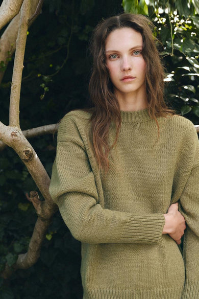 T-shirt vert avec col rond de MANGO, vu de derrière, associé à une jupe sombre et des gants en cuir longs.