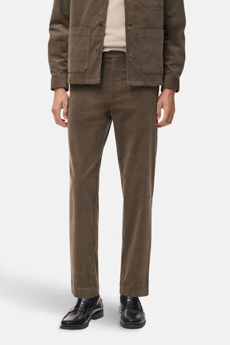 Pantalon marron de MANGO, en cuir de corduroy, associé à des loafers noirs en cuir et une veste coordonnée.