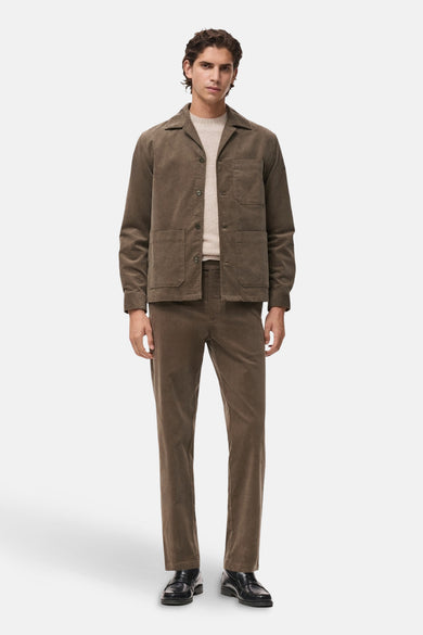 Grijs, lange mouwen hemd van MANGO, gedragen onder een bruine corduroy jas met bijpassende broek en zwarte schoenen.

