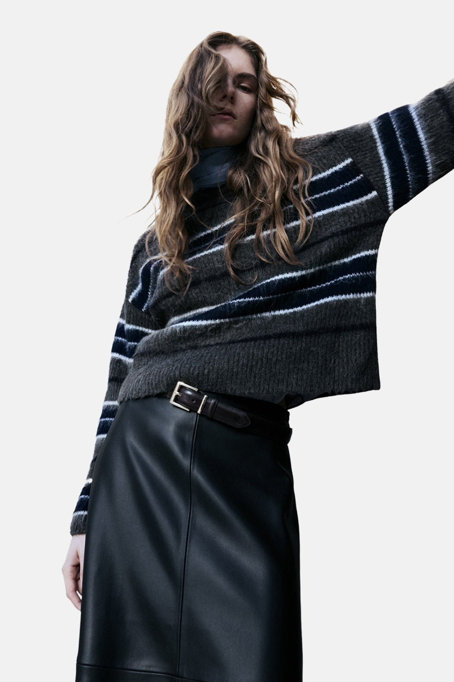 Vrouw in gestreepte trui en zwarte leren rok.
