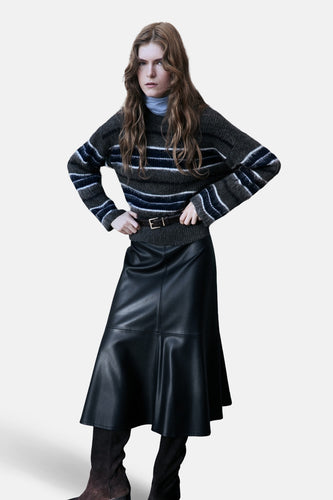 Vrouw met gestreepte trui, leren rok en laarzen.